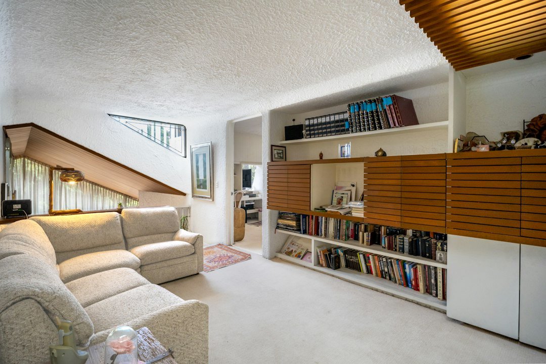 A beige sofa in a living room with built-in wooden shelving and books